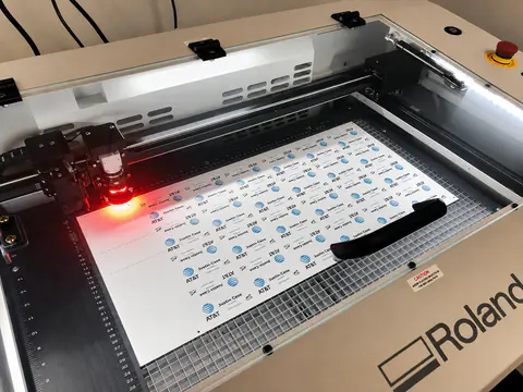 Flatbed laser cutting a sheet of pre-printed name badges.