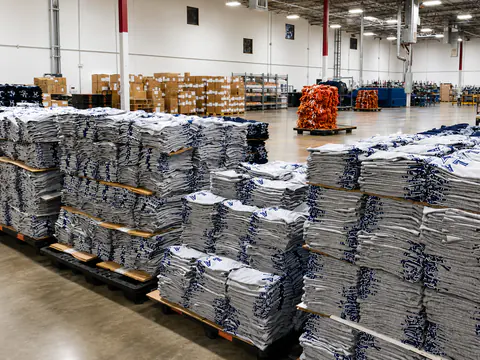 Large stacks of decorated gray garments across the production floor