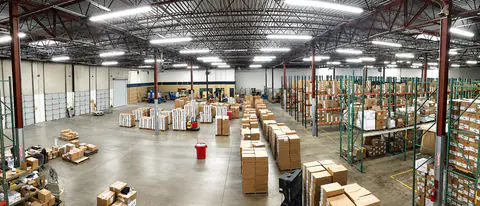 Wide view of the Impress Designs warehouse with pallet racking and boxed inventory