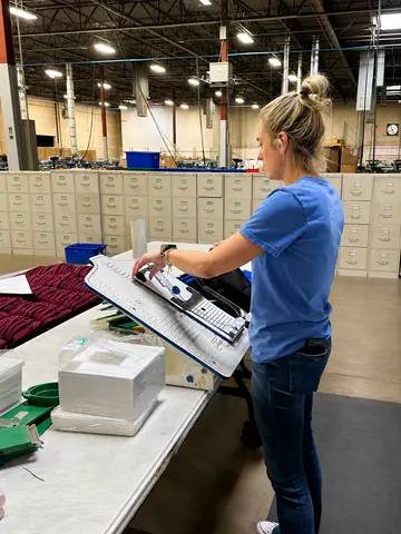 Production employee inspecting a garment at an embroidery station